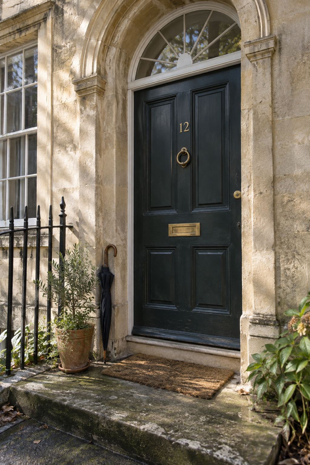 A dark green front door set in a stone Georgian doorway